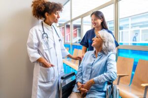 A caregiver assists an elderly woman while reviewing a care plan together at a table.